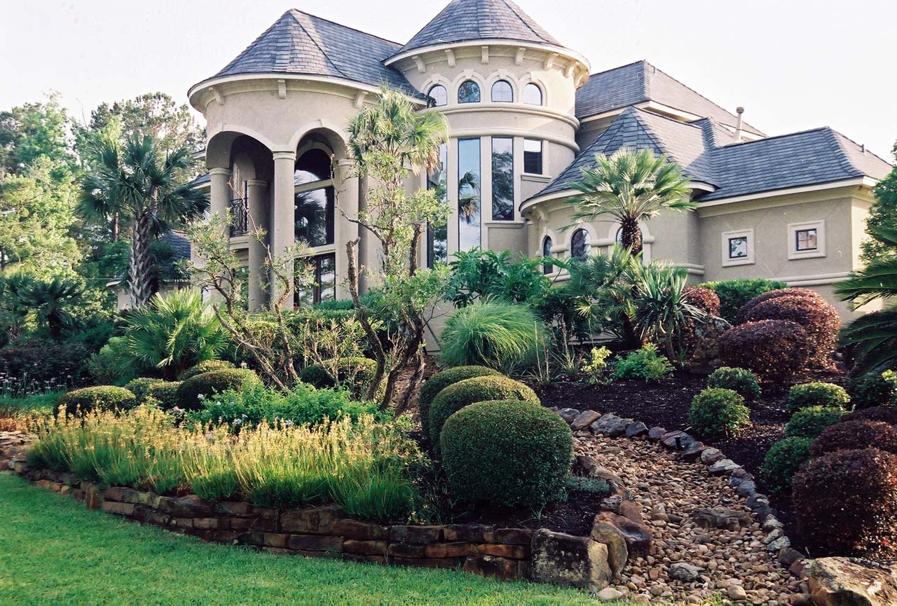 Large-lot estate landscape with layered planting beds and palm trees Montgomery TX — New Yards Landscaping